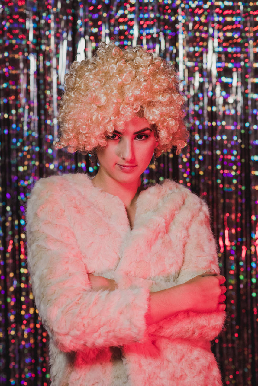 Chica rubia disfrutando con su peluca mientras usa RETROMATA, tu fotomatón para bodas en Málaga